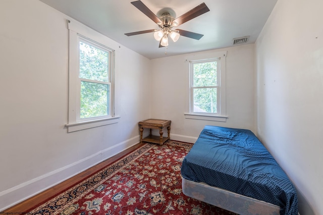 bedroom with multiple windows, wood-type flooring, and ceiling fan