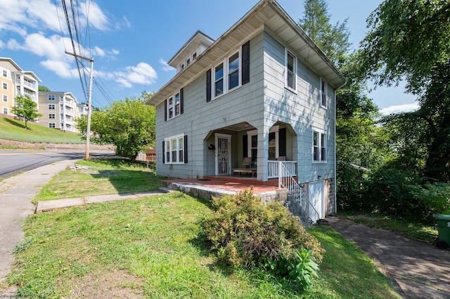 view of front facade with a garage, a porch, and a front lawn