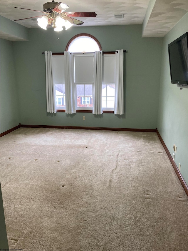 spare room featuring ceiling fan, a healthy amount of sunlight, and light carpet