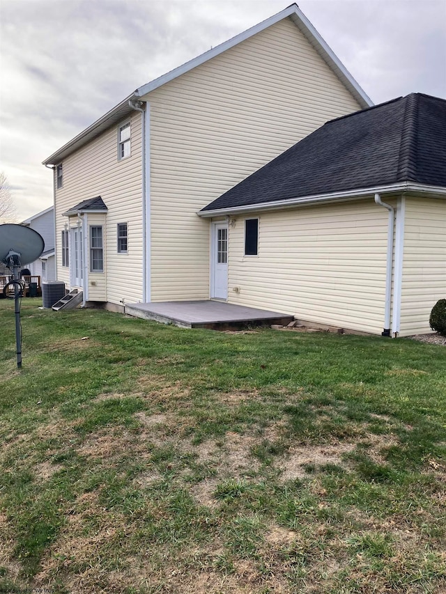 rear view of property featuring central air condition unit, a lawn, and a patio area