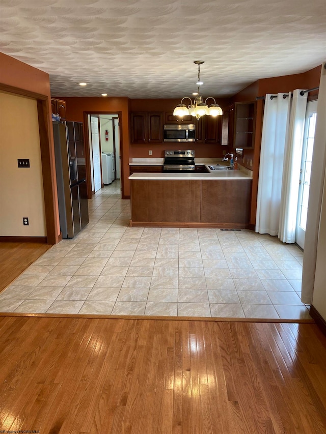 kitchen with stainless steel appliances, light hardwood / wood-style flooring, and an inviting chandelier