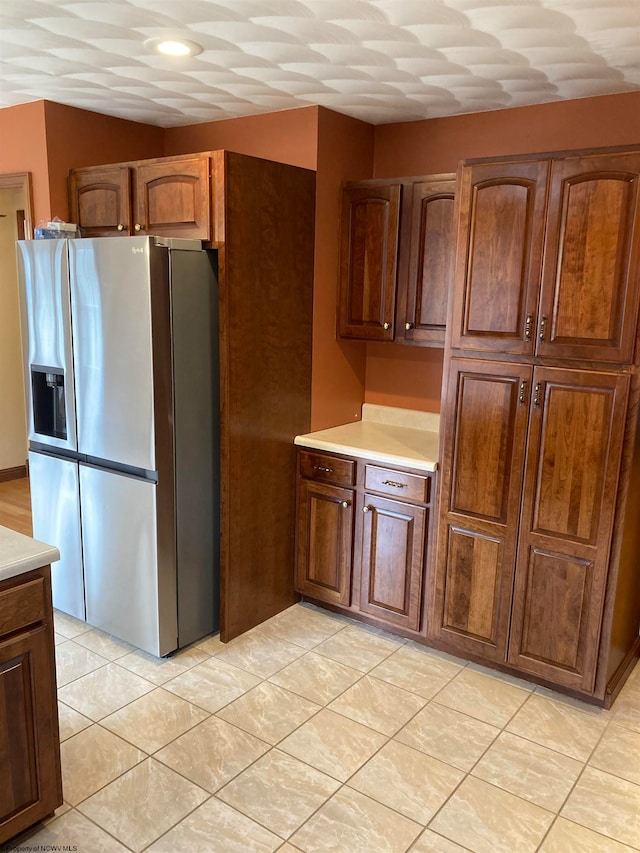 kitchen featuring stainless steel fridge with ice dispenser and light tile patterned flooring