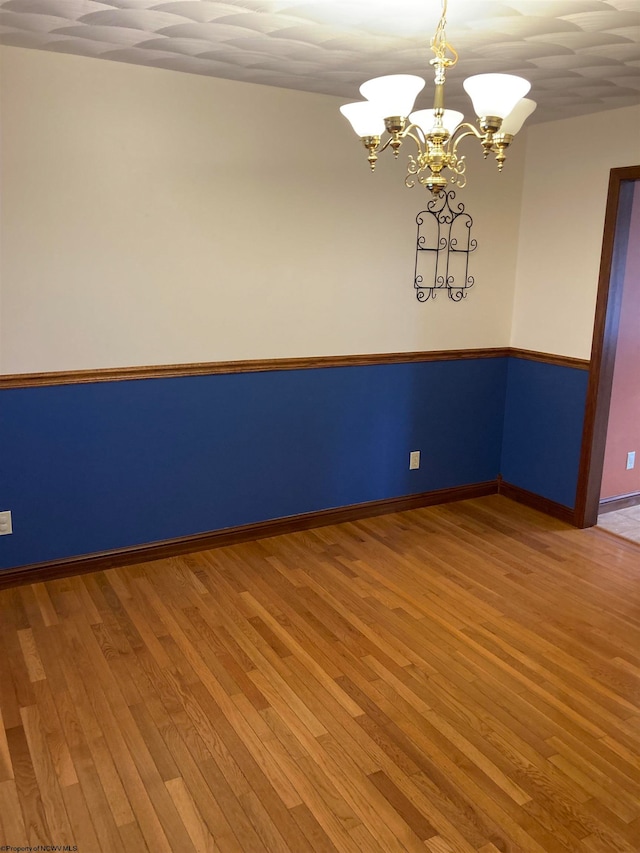 empty room featuring a chandelier and hardwood / wood-style floors