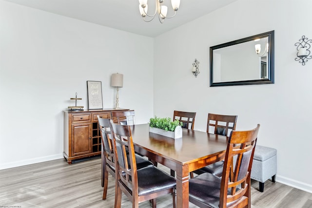 dining area with wood-type flooring and an inviting chandelier