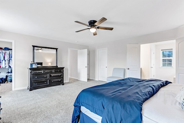 bedroom with a closet, a spacious closet, light carpet, and ceiling fan