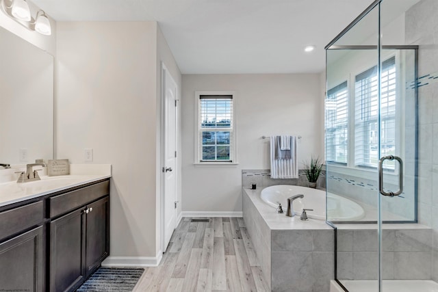 bathroom featuring a wealth of natural light, hardwood / wood-style flooring, and separate shower and tub