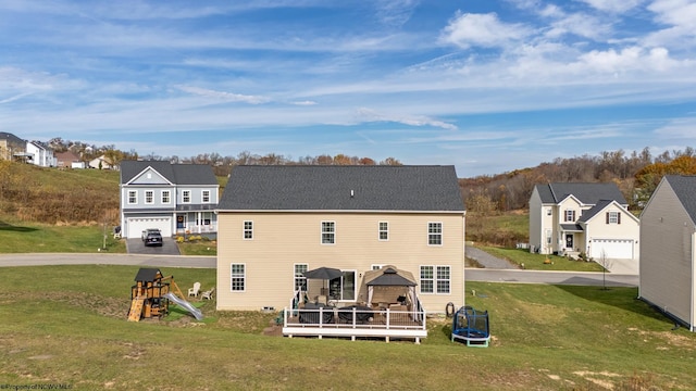 rear view of house featuring a garage, a yard, and a deck