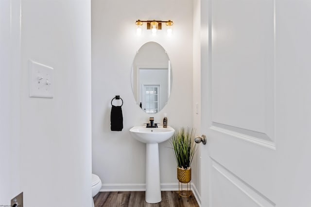 bathroom with toilet, sink, and hardwood / wood-style flooring