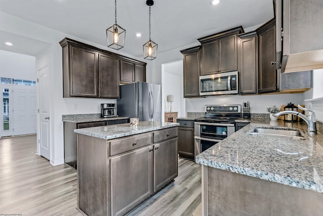 kitchen with dark brown cabinetry, light hardwood / wood-style flooring, sink, a kitchen island, and appliances with stainless steel finishes