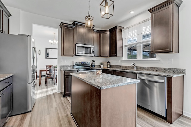 kitchen featuring light hardwood / wood-style flooring, hanging light fixtures, a kitchen island, dark brown cabinets, and appliances with stainless steel finishes