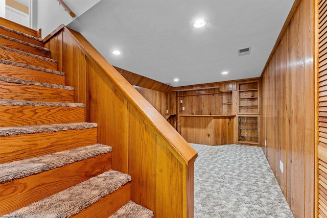 staircase with wood walls and carpet flooring