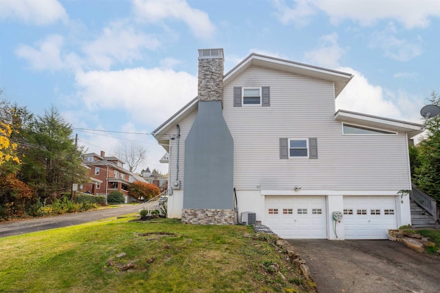 view of property exterior with a lawn, a garage, and central AC