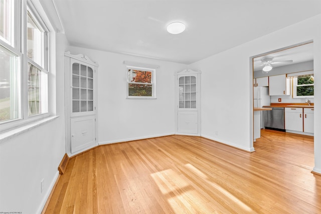 unfurnished room with light wood-type flooring, sink, and ceiling fan