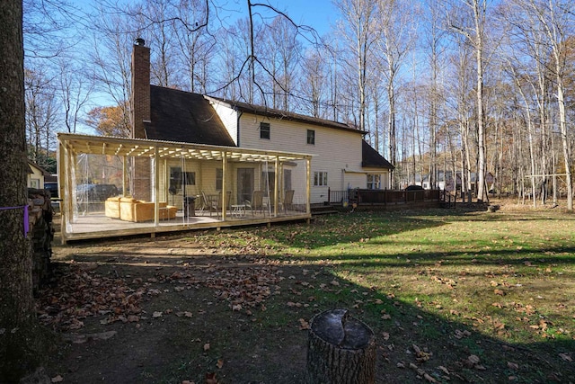 rear view of house featuring a wooden deck and a lawn