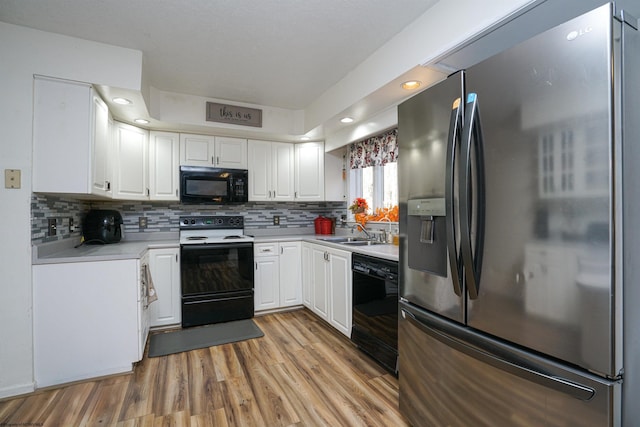 kitchen with white cabinetry, light hardwood / wood-style floors, black appliances, and tasteful backsplash