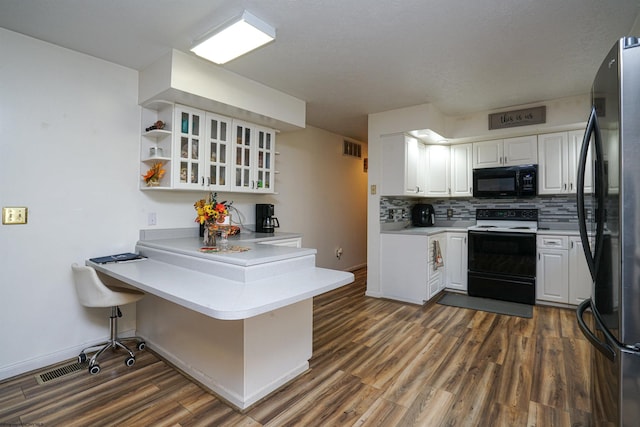 kitchen featuring stainless steel refrigerator, white cabinetry, kitchen peninsula, a breakfast bar area, and white electric range