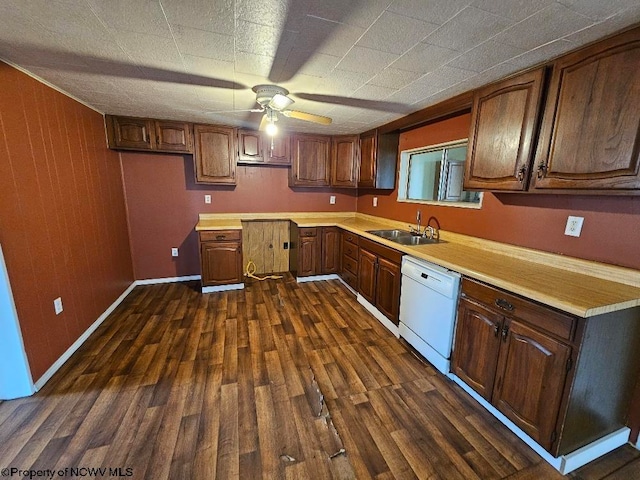 kitchen featuring dark wood-type flooring, wood walls, sink, dishwasher, and ceiling fan