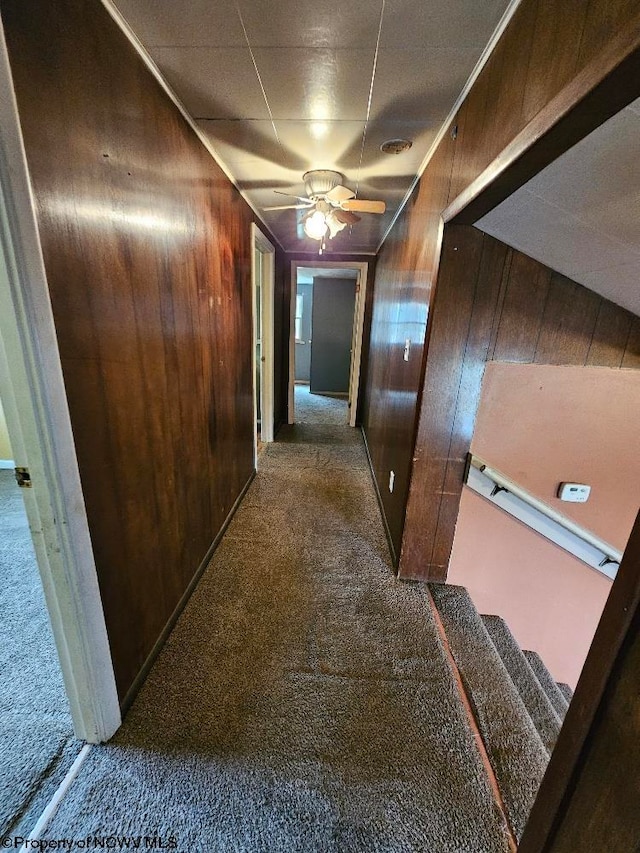 hallway featuring dark colored carpet and wooden walls