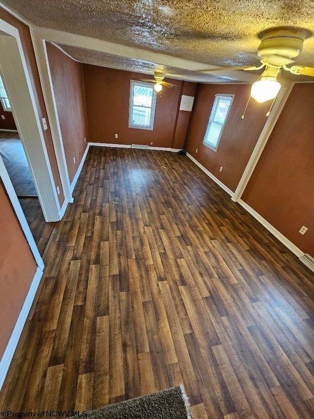 interior space featuring dark wood-type flooring, a wealth of natural light, and a textured ceiling