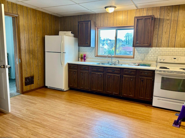 kitchen featuring wood walls, a drop ceiling, white appliances, and sink