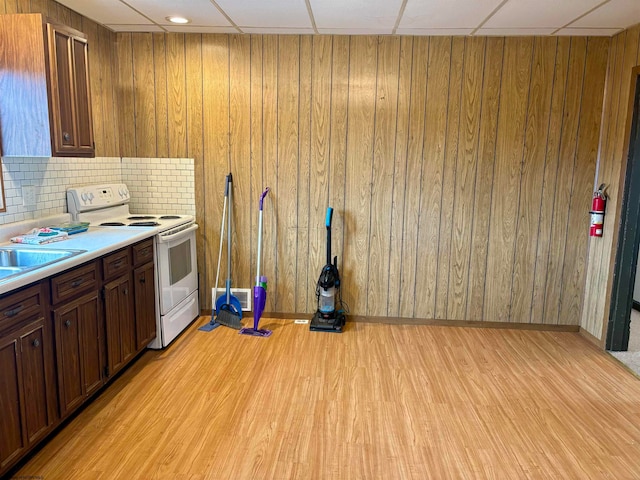 kitchen featuring light wood-type flooring, wooden walls, and white electric stove