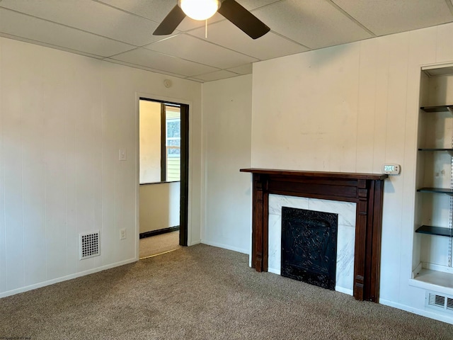 unfurnished living room featuring a premium fireplace, ceiling fan, and carpet floors