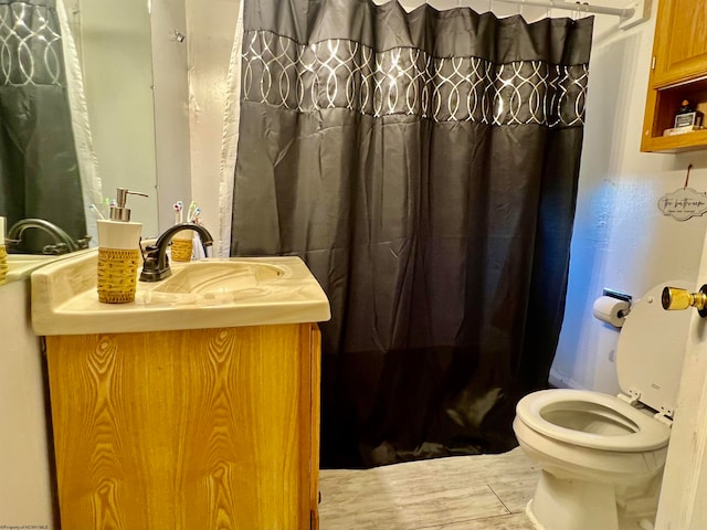 bathroom with toilet, vanity, wood-type flooring, and walk in shower