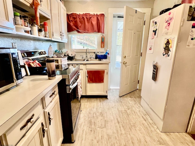 kitchen with stainless steel appliances, sink, and light hardwood / wood-style flooring