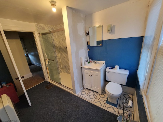 bathroom featuring toilet, vanity, tile patterned flooring, and a shower with shower door