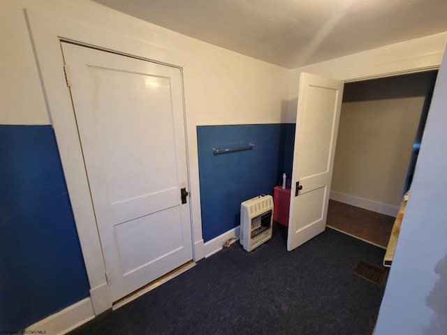 unfurnished bedroom with heating unit and a closet