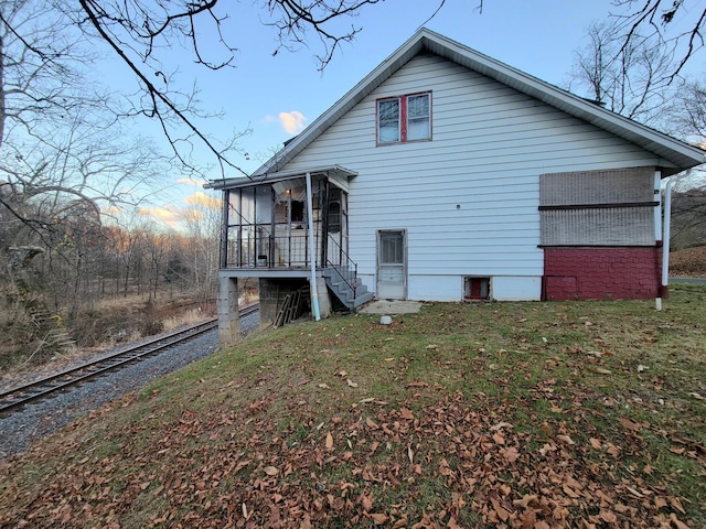 rear view of house featuring a lawn and a sunroom