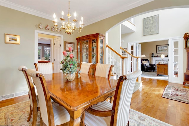 dining room with ornamental molding, an inviting chandelier, and light hardwood / wood-style floors