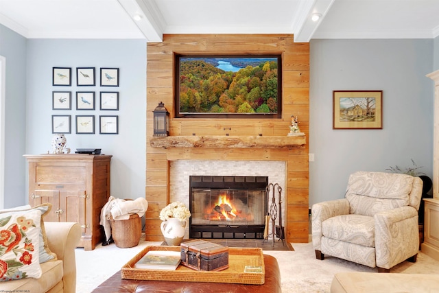 living area featuring a fireplace, beamed ceiling, wood walls, and ornamental molding