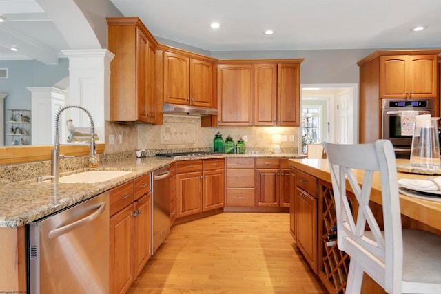 kitchen with stainless steel appliances, sink, tasteful backsplash, light hardwood / wood-style flooring, and ornate columns