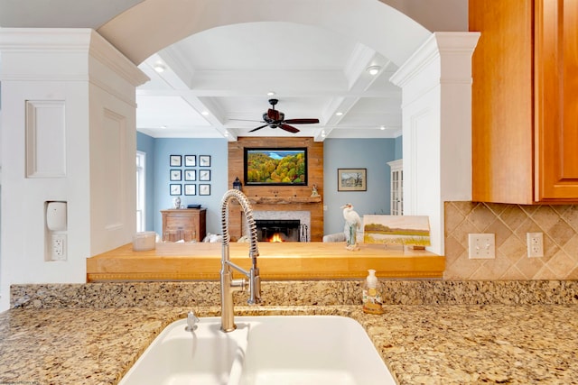 kitchen with beamed ceiling, sink, coffered ceiling, and light stone countertops