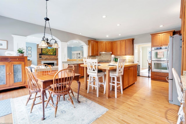 dining area featuring a fireplace, light hardwood / wood-style floors, and an inviting chandelier