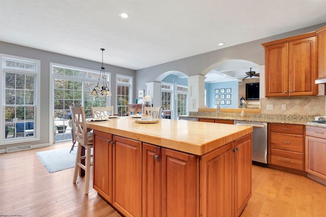 kitchen with light hardwood / wood-style flooring, a center island, hanging light fixtures, and stainless steel appliances