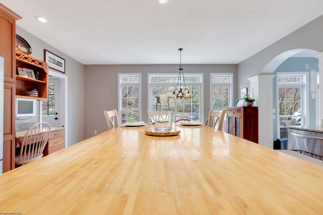 dining space with decorative columns, a chandelier, and wood-type flooring