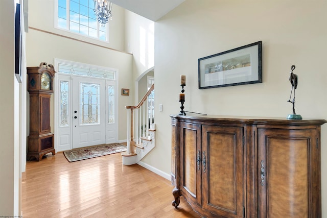 entryway featuring a towering ceiling, a chandelier, and light hardwood / wood-style flooring