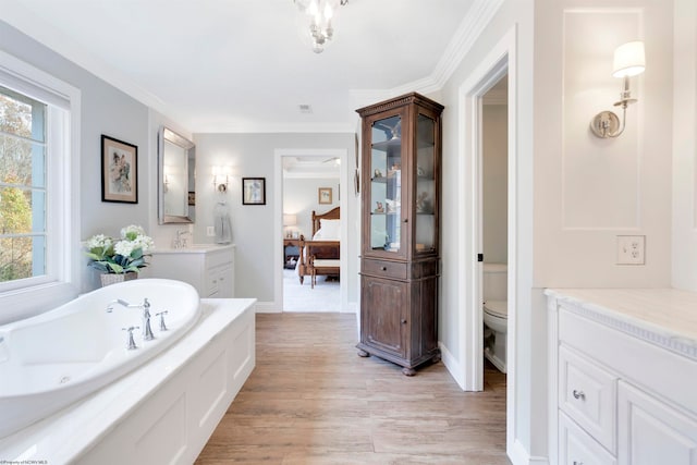 bathroom with toilet, hardwood / wood-style flooring, vanity, crown molding, and a bath