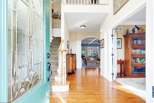 foyer featuring ornate columns, wood-type flooring, ceiling fan, and crown molding