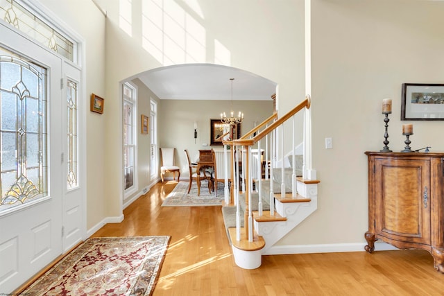 entryway with a high ceiling, hardwood / wood-style floors, and a notable chandelier