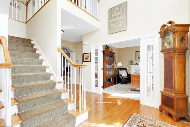 entryway with a towering ceiling and light wood-type flooring