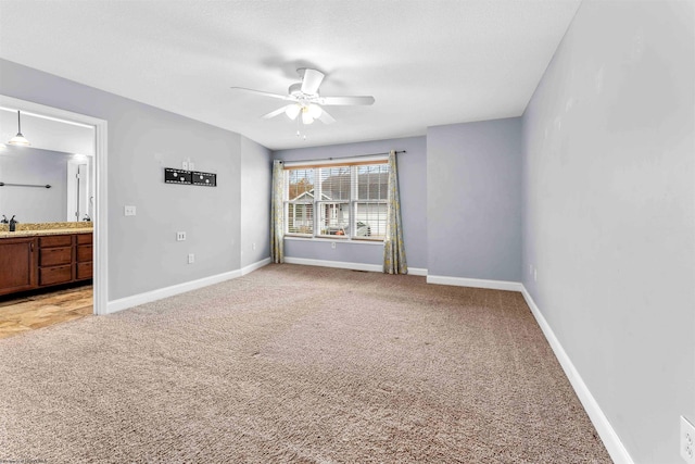 spare room featuring light carpet, ceiling fan, and sink