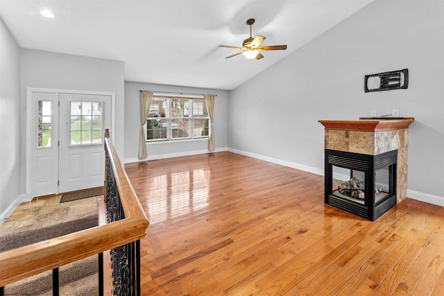 foyer entrance with a multi sided fireplace, ceiling fan, wood-type flooring, and vaulted ceiling