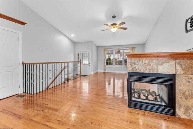 unfurnished living room featuring light wood-type flooring, vaulted ceiling, ceiling fan, and a fireplace