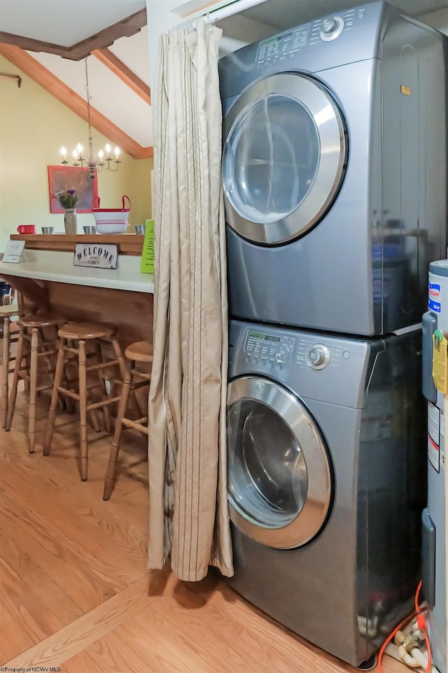 laundry area with electric water heater, stacked washer and clothes dryer, light hardwood / wood-style flooring, and a notable chandelier