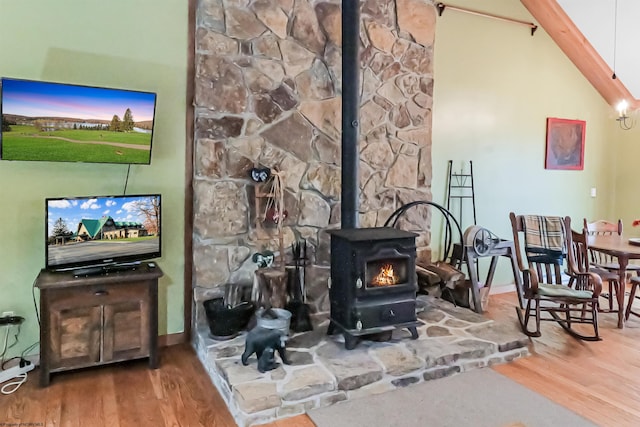 living room featuring hardwood / wood-style floors, a wood stove, and lofted ceiling