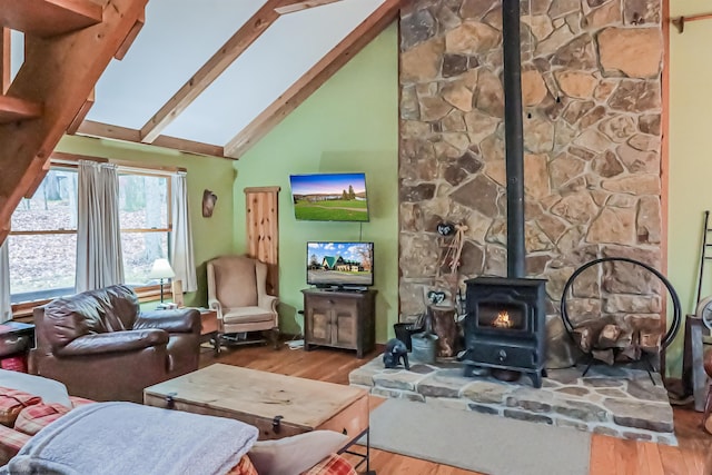 living room featuring beam ceiling, high vaulted ceiling, a skylight, wood-type flooring, and a wood stove