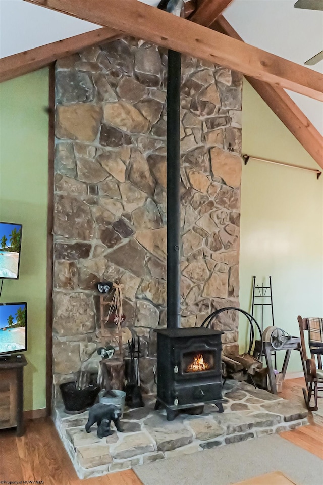 interior details featuring hardwood / wood-style floors, beam ceiling, and a wood stove